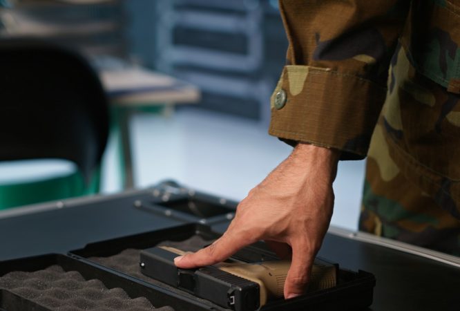 Military officer checking handguns in command room, ensuring bullets and supplies are working properly. Close up of soldier holding pistol, managing combat load equipment, camera A