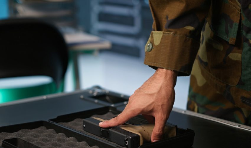 Close up of soldier holding pistol, managing combat load equipment Military officer checking handguns in command room, ensuring bullets and supplies are working properly. Close up of soldier holding pistol, managing combat load equipment, camera A