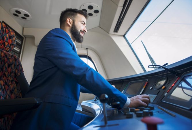 Professional driver sitting in cockpit and operating high speed train.