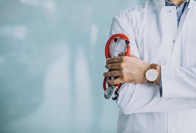 Young handsome physician in a medical robe with stethoscope
